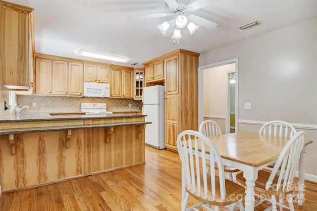 2196 Uphill Ln, Lenoir, NC 28645 - kitchen featuring white appliances, a peninsula, dark stone counters, light wood-type flooring, and backsplash