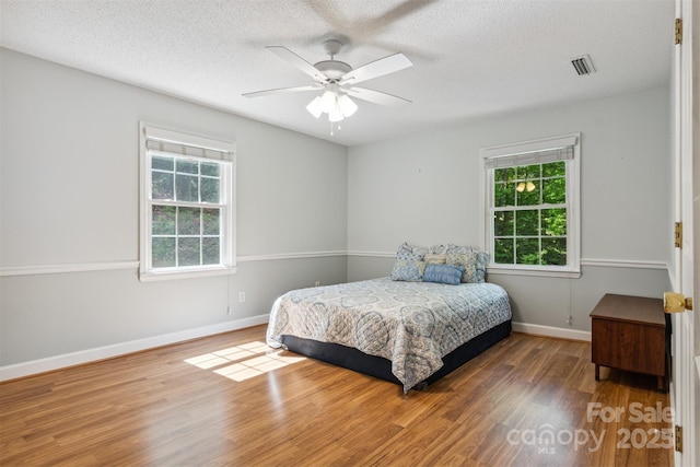 2196 Uphill Ln, Lenoir, NC 28645 - bedroom with multiple windows, wood finished floors, a textured ceiling, baseboards, and ceiling fan