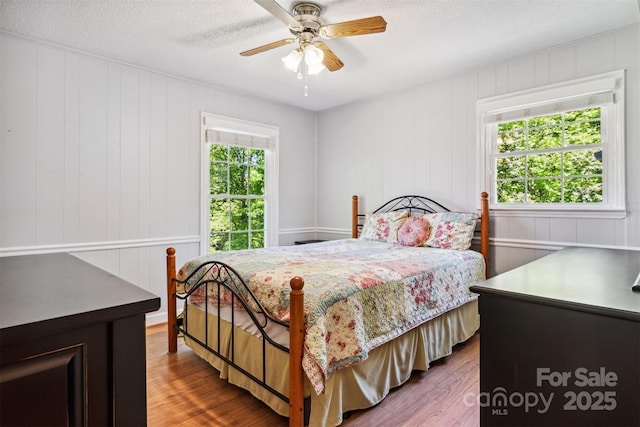 2196 Uphill Ln, Lenoir, NC 28645 - bedroom with multiple windows, wood finished floors, a decorative wall, a textured ceiling, and ceiling fan