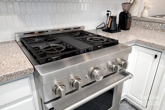 44 White Thorn Dr, Alexander, NC 28701 - details featuring backsplash, white cabinetry, light stone counters, and stainless steel stove