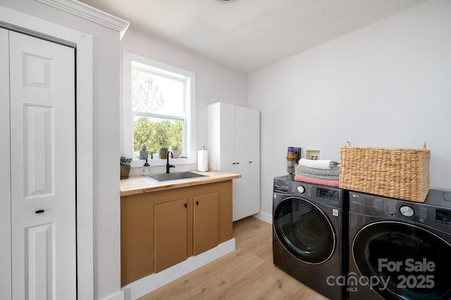 44 White Thorn Dr, Alexander, NC 28701 - clothes washing area featuring washing machine and dryer, baseboards, light wood-type flooring, a sink, and cabinet space