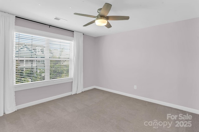 carpeted spare room with baseboards, ceiling fan, and visible vents
