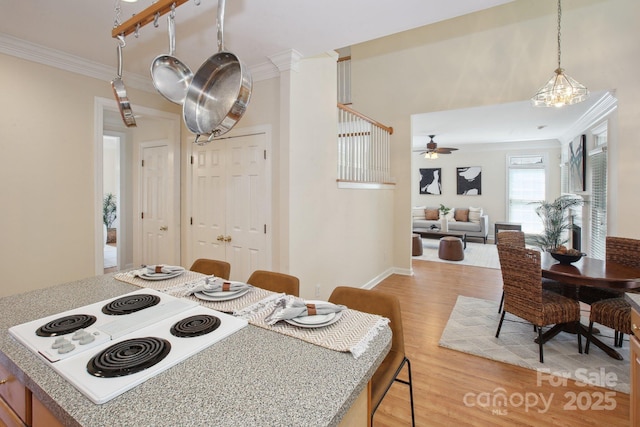 dining room featuring light wood-style floors, ornamental molding, baseboards, and a ceiling fan