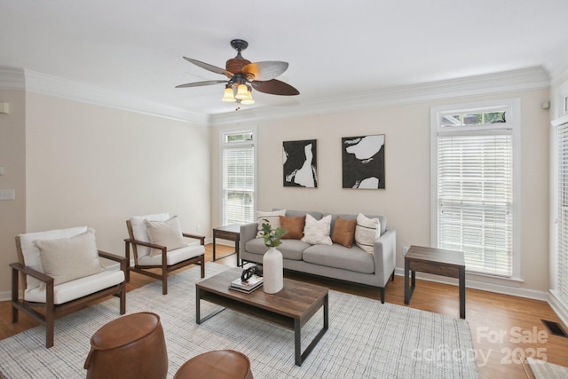 living area featuring baseboards, ornamental molding, a wealth of natural light, and light wood finished floors