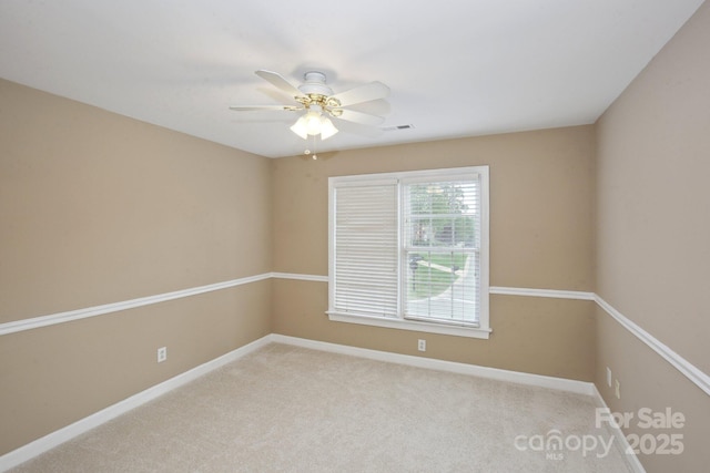 empty room featuring a ceiling fan, baseboards, visible vents, and light carpet