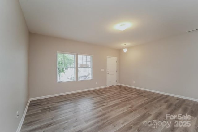 spare room featuring wood finished floors and baseboards