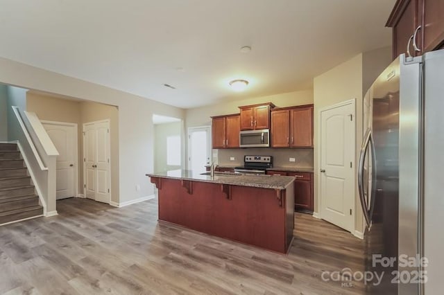 kitchen featuring appliances with stainless steel finishes, a sink, a breakfast bar area, and wood finished floors