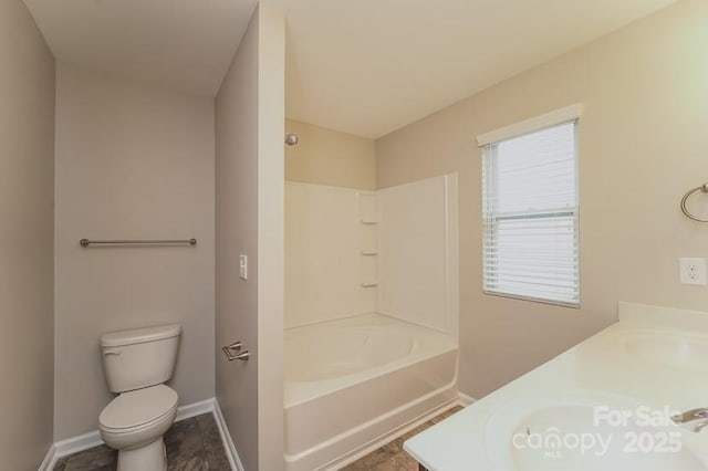 bathroom featuring baseboards, toilet, and double vanity