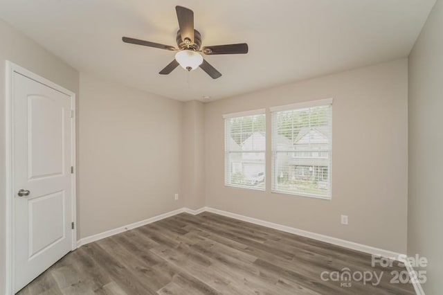 unfurnished room with wood finished floors, baseboards, and a ceiling fan