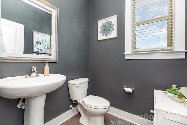 half bath featuring baseboards and toilet