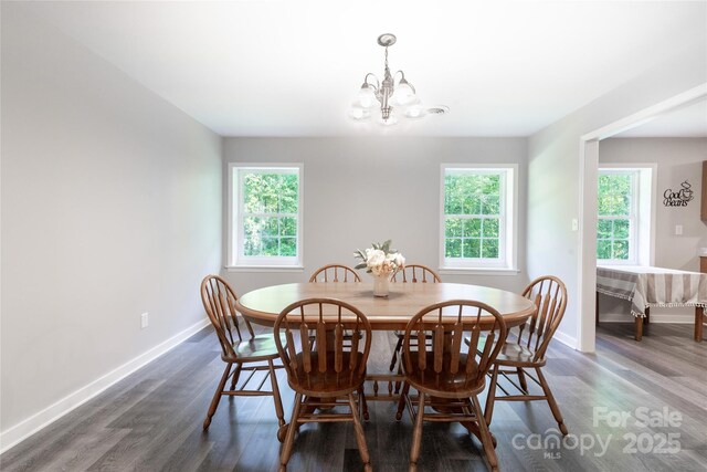 dining space featuring baseboards, wood finished floors, and a notable chandelier