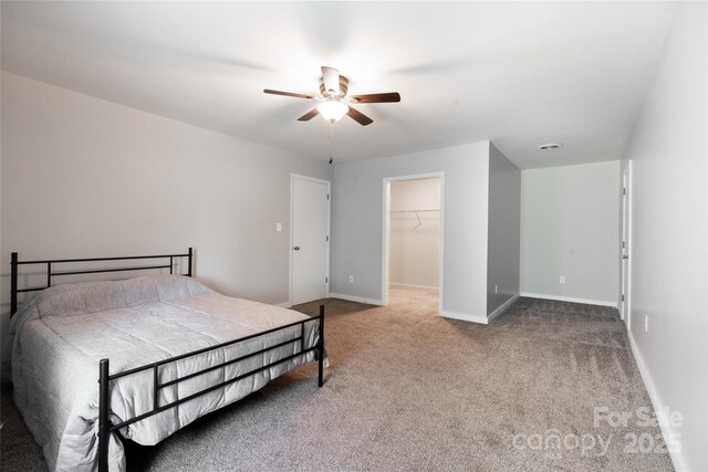 bedroom with a closet, baseboards, ceiling fan, a spacious closet, and carpet