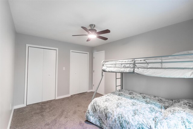 bedroom with multiple closets, ceiling fan, baseboards, and carpet flooring