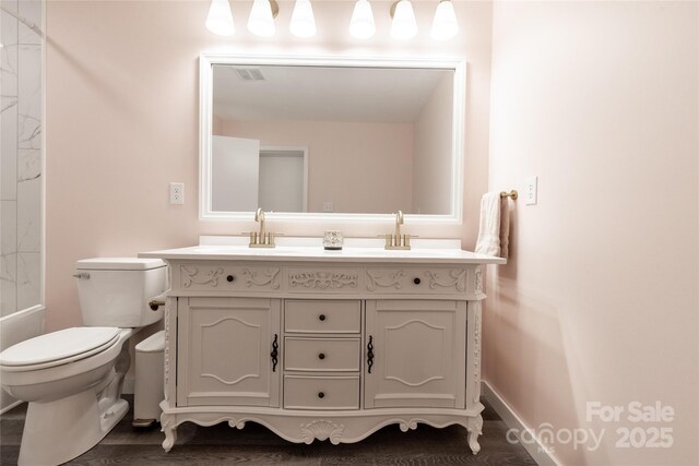 bathroom featuring double vanity, toilet, a sink, and visible vents