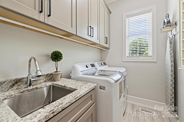 laundry area with baseboards, visible vents, a sink, separate washer and dryer, and cabinet space