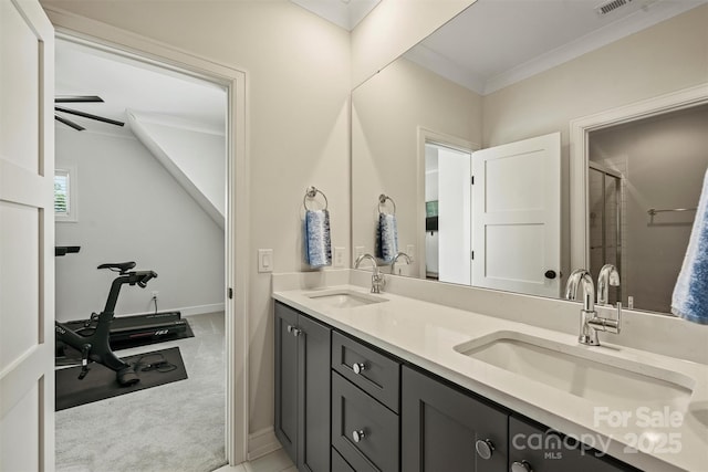 bathroom with double vanity, crown molding, a stall shower, and a sink