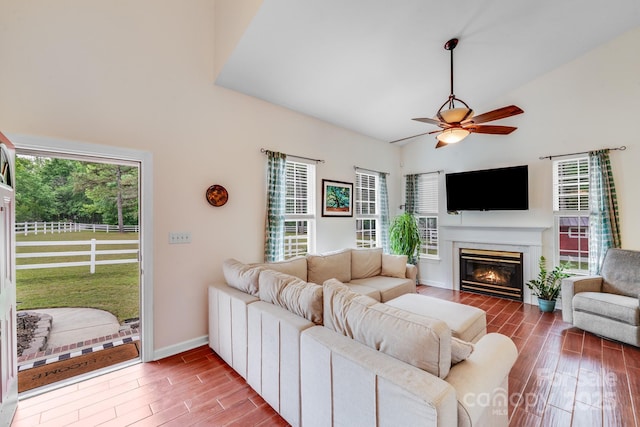 6910 Birdsong Ln, Waxhaw, NC 28173 - living room with wood finished floors, high vaulted ceiling, ceiling fan, a glass covered fireplace, and baseboards