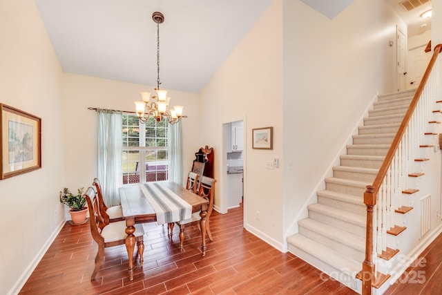 6910 Birdsong Ln, Waxhaw, NC 28173 - dining space featuring a chandelier, baseboards, stairs, wood finished floors, and vaulted ceiling