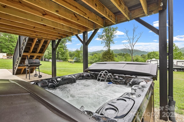 view of patio with a hot tub, a mountain view, and a grill