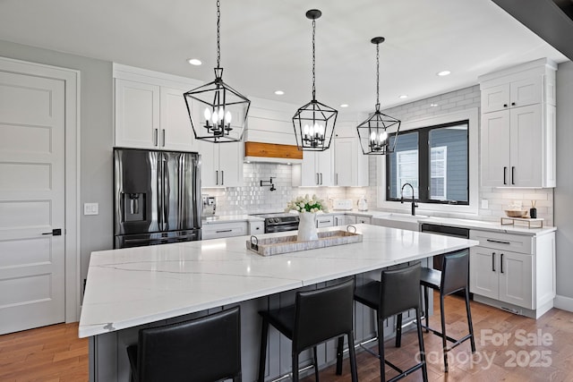 kitchen with a notable chandelier, appliances with stainless steel finishes, a sink, and tasteful backsplash