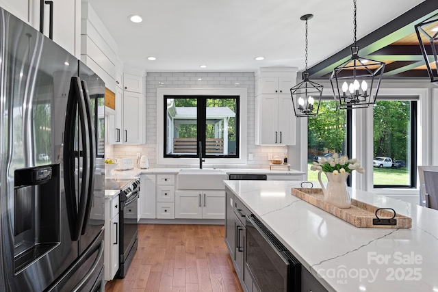 kitchen with a sink, black appliances, white cabinetry, and a wealth of natural light