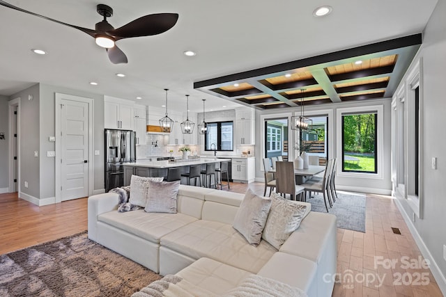 living area featuring beam ceiling, light wood-style flooring, recessed lighting, baseboards, and coffered ceiling
