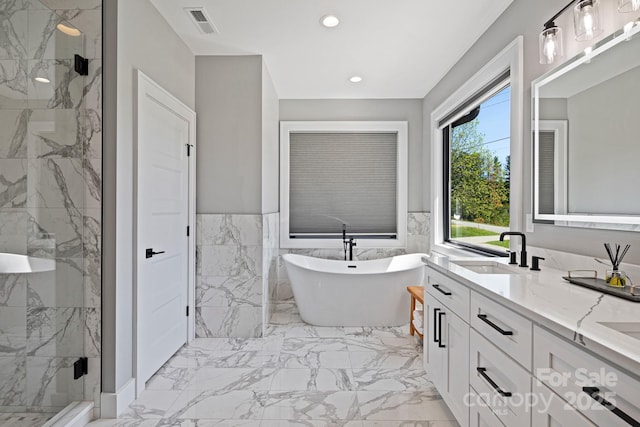 full bath with a freestanding bath, a sink, marble finish floor, a marble finish shower, and recessed lighting