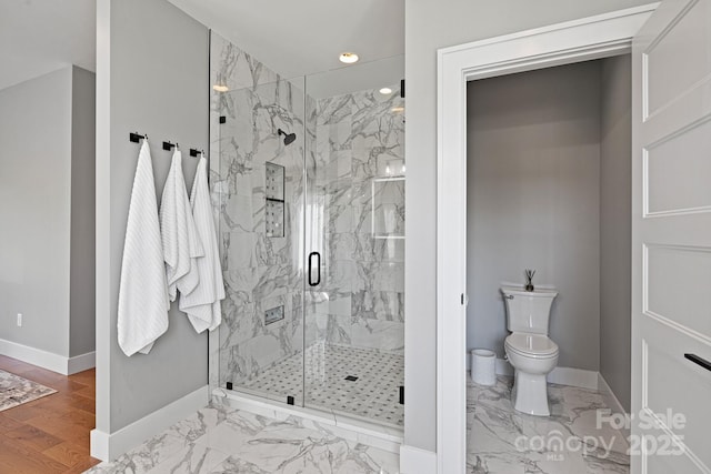 bathroom featuring toilet, baseboards, a marble finish shower, and marble finish floor