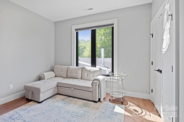 living area with baseboards, wood finished floors, and visible vents