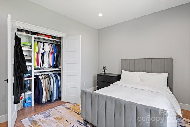 bedroom with recessed lighting, baseboards, wood finished floors, and a closet