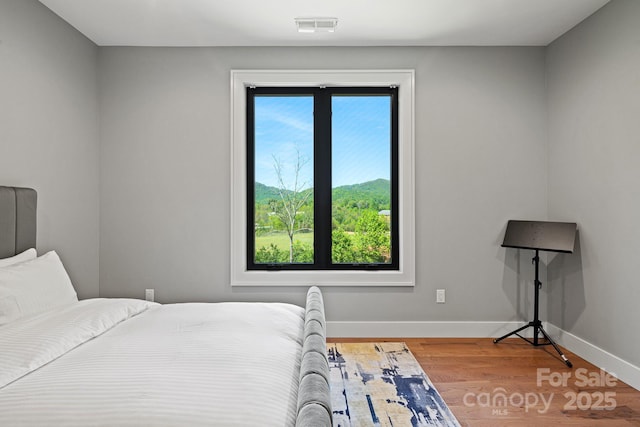 bedroom with baseboards, wood finished floors, and visible vents