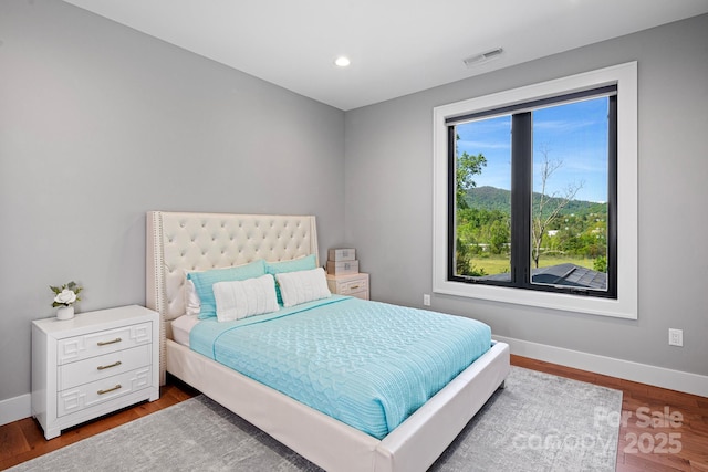 bedroom with baseboards, recessed lighting, wood finished floors, and visible vents