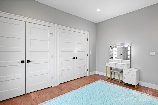bedroom with recessed lighting, baseboards, multiple closets, and wood finished floors