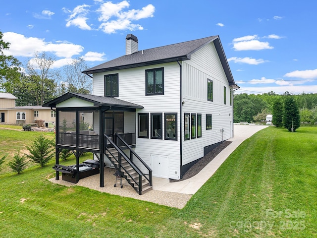 rear view of house featuring a chimney, a yard, stairs, a sunroom, and roof with shingles