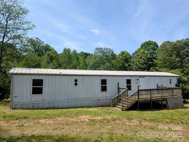 rear view of property with a wooded view, a deck, and metal roof