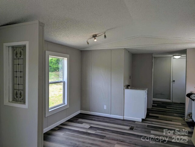 unfurnished room featuring baseboards, a textured ceiling, and wood finished floors
