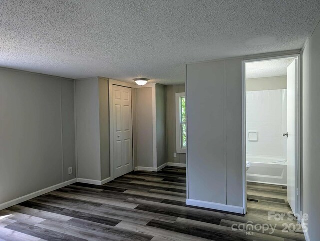 spare room featuring baseboards, dark wood finished floors, and a textured ceiling