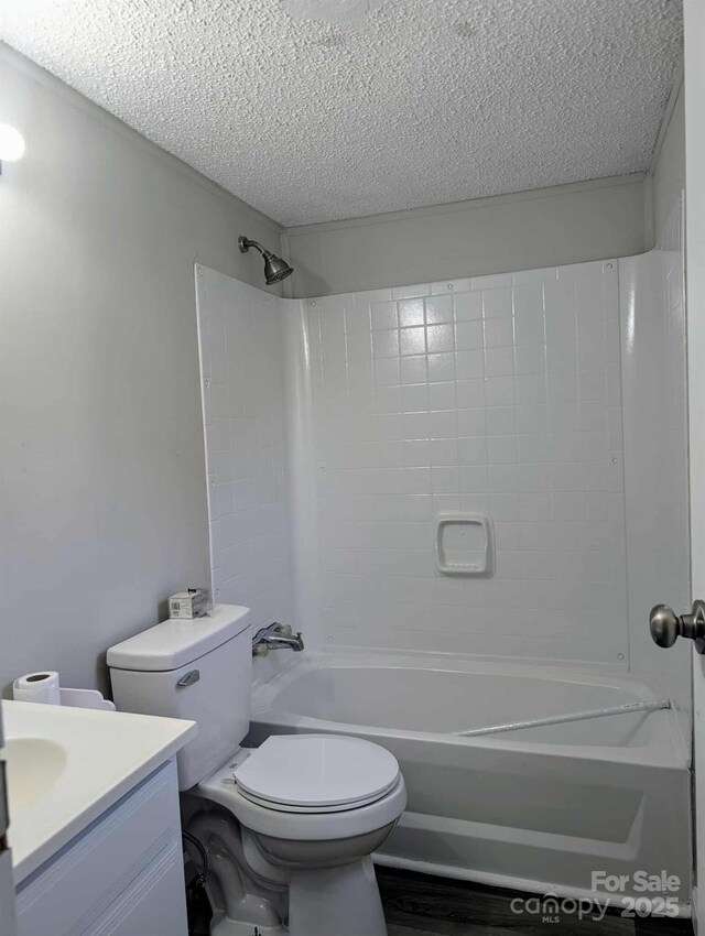 full bath with vanity, toilet, a textured ceiling, and shower / washtub combination