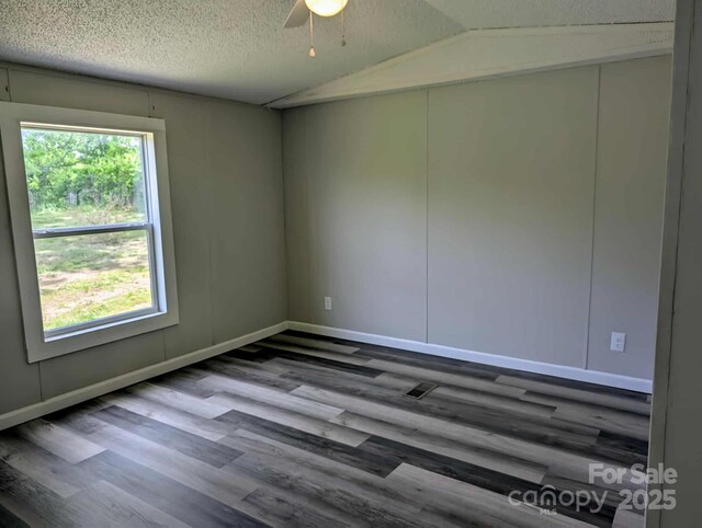 unfurnished room featuring wood finished floors, baseboards, a textured ceiling, a ceiling fan, and vaulted ceiling