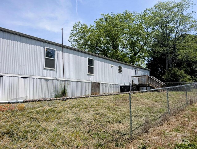 view of side of property with fence, a yard, central AC, and stairway