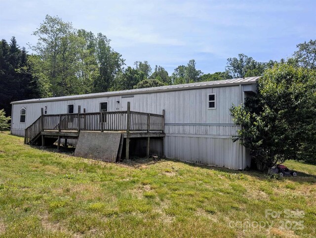 rear view of house with a yard, a deck, and metal roof