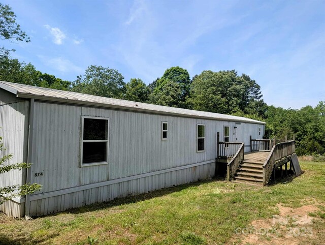 rear view of property featuring a yard, a wooden deck, and metal roof