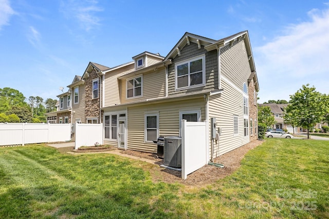 rear view of property with fence, a lawn, and cooling unit