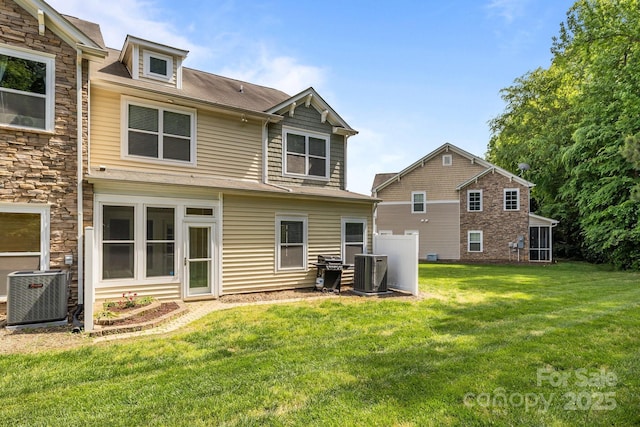 back of house featuring a lawn, cooling unit, and stone siding