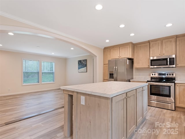kitchen featuring a kitchen island, crown molding, appliances with stainless steel finishes, and light wood-style floors