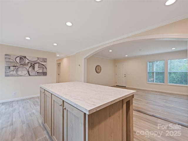 kitchen with light wood-style floors, arched walkways, a center island, recessed lighting, and ornamental molding