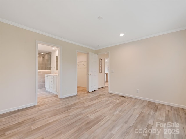 unfurnished bedroom with a walk in closet, crown molding, baseboards, recessed lighting, and light wood-style flooring