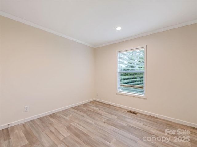 empty room featuring crown molding, baseboards, visible vents, and light wood-style floors