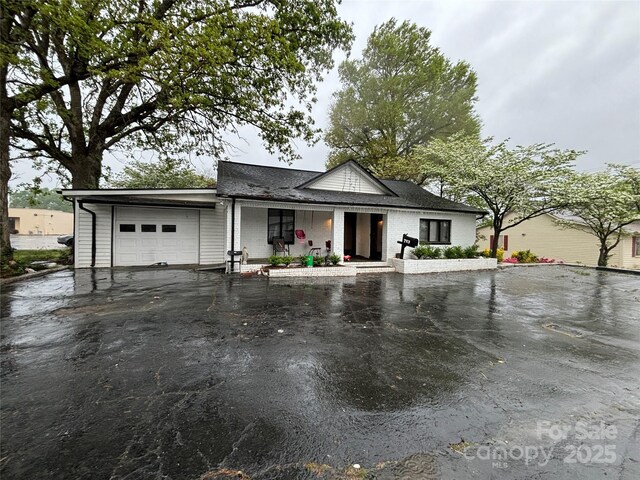 view of front of house featuring an attached garage, aphalt driveway, and a porch