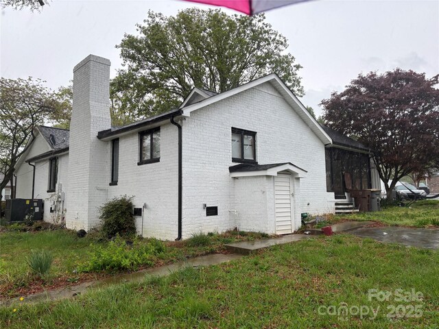 view of property exterior with brick siding, a chimney, central AC unit, and entry steps